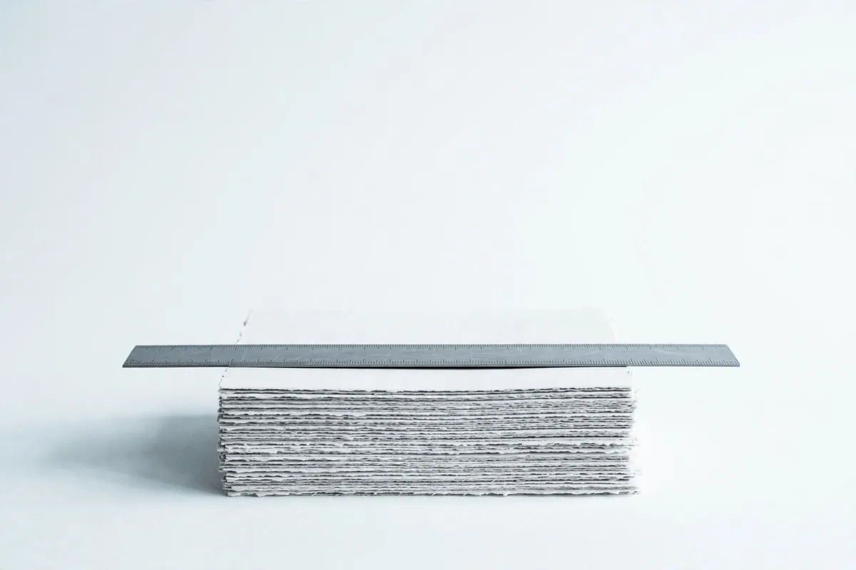 A steel ruler lying across a stack of paper